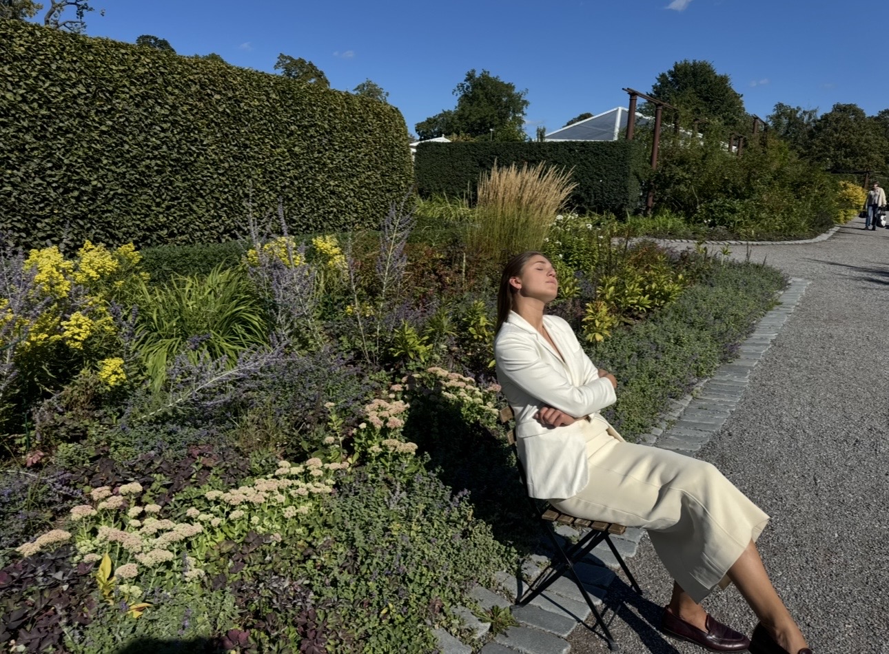Person in a white jacket sitting in a garden chair on a sunny day